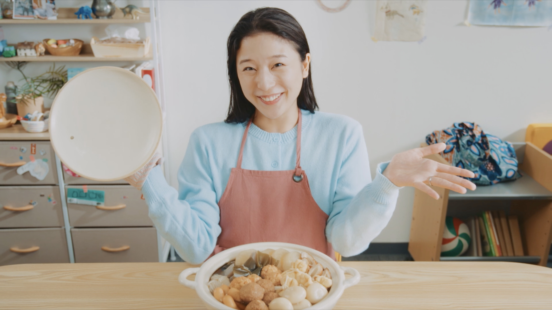 おでん鍋のまえで両手を開く人